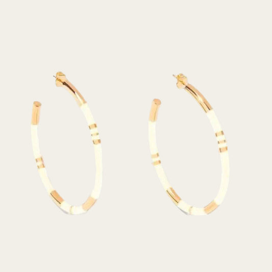 Aurélie Bidermann Positano earrings, featuring ivory-colored stripes in resin and gilded with 750/1000 yellow gold. On flat lay neutral